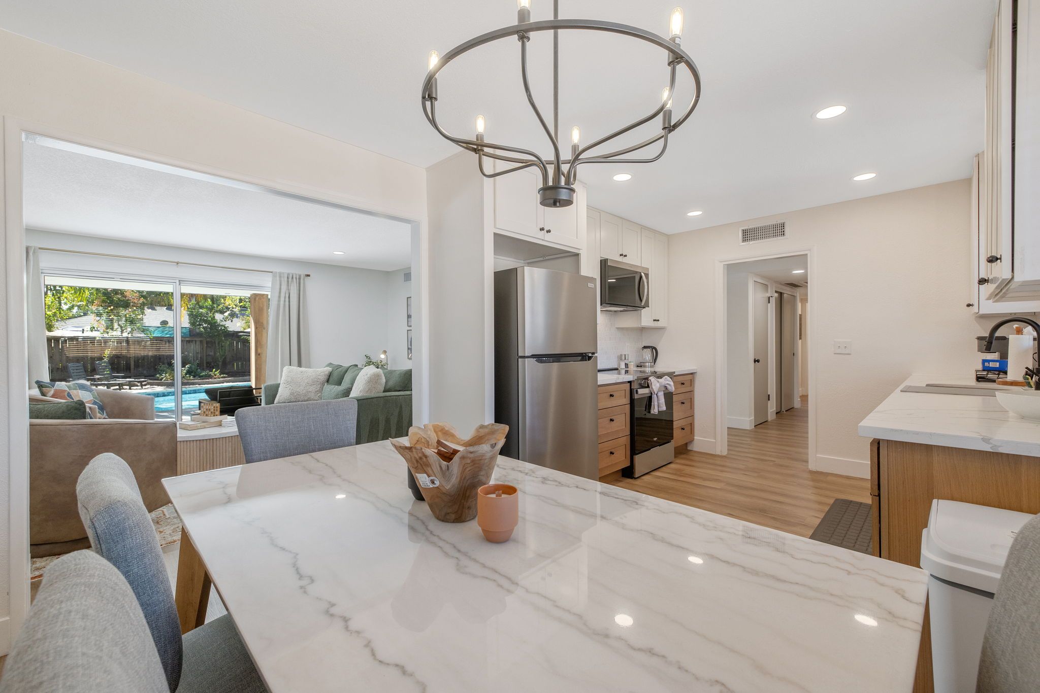 A modern kitchen with a central island, stainless steel appliances, and a dining area with a marble table.