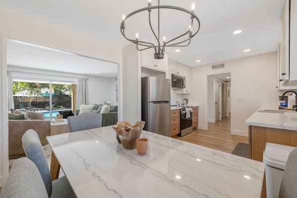 A modern kitchen with a central island, stainless steel appliances, and a dining area with a marble table.