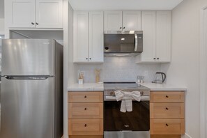 Una cocina moderna con electrodomésticos de acero inoxidable, armarios blancos y encimera de mármol.