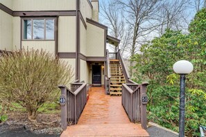 The property entrance features a private wooden walkway leading to your unit, surrounded by mature trees and natural landscaping that create a peaceful, secluded atmosphere. - Elegant 2 Bedroom Condo on the Golf Course at Sugar Mountain (Sugar Mountain)