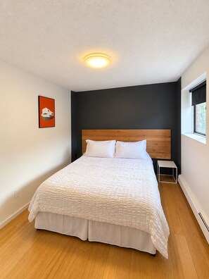 Ein Schlafzimmer mit einem hölzernen Kopfende, einer weißen Bettdecke und einem kleinen Nachttisch.