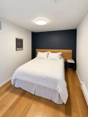 Ein Schlafzimmer mit Bett, Nachttisch, Wandlampe und Deckenleuchte.