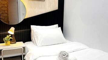 Een hotelkamer met een bed, een nachtkastje met een lamp, een spiegel en een ingelijst schilderij aan de muur.