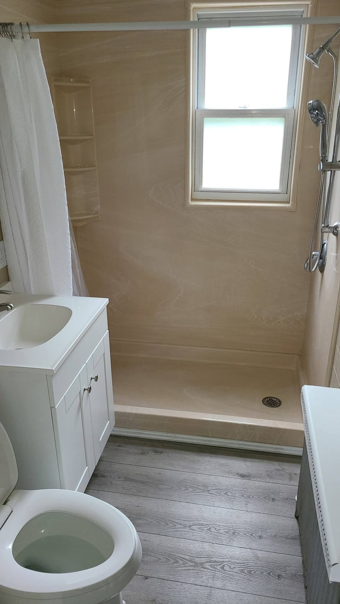 A bathroom with a shower, toilet, and sink.