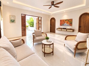 A spacious living room with a sofa, two armchairs, a coffee table, and a ceiling fan. - Beachfront Villa Gành Dầu 5Brs by Anamoi (Phú Quốc)