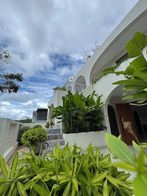 A white building with a balcony, surrounded by lush green plants. - Beachfront Villa Gành Dầu 5Brs by Anamoi (Phú Quốc)