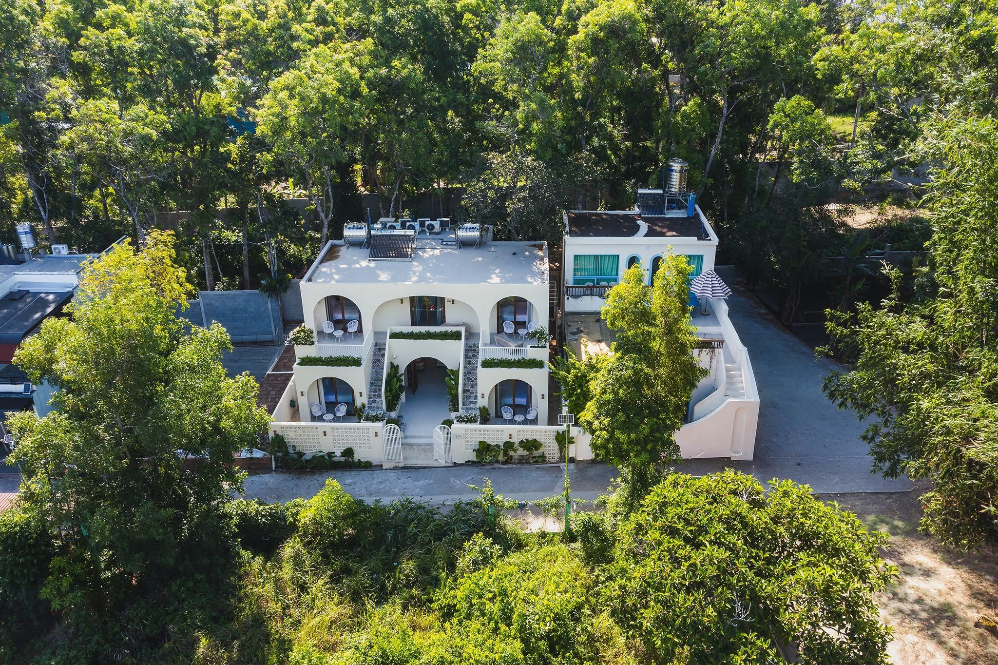 A two-story building with a central courtyard, surrounded by dense greenery.