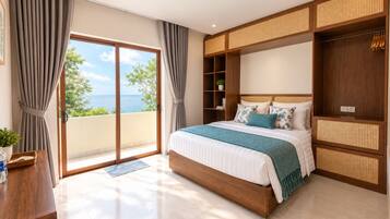 A bedroom with a large bed, a wooden wardrobe, and a view of the sea.