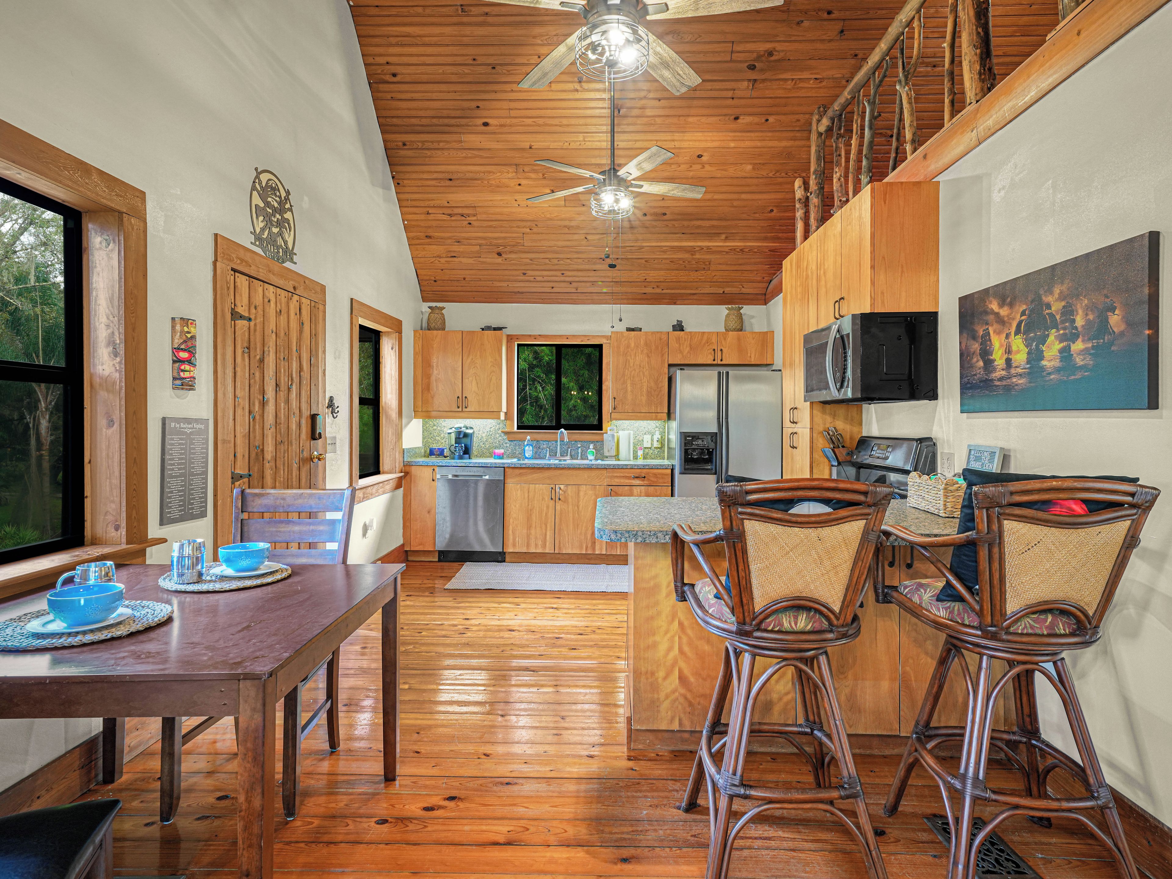 Un interior de madera con comedor, cocina y ventilador de techo.