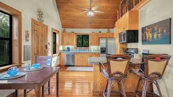 Un interior de madera con comedor, cocina y ventilador de techo.