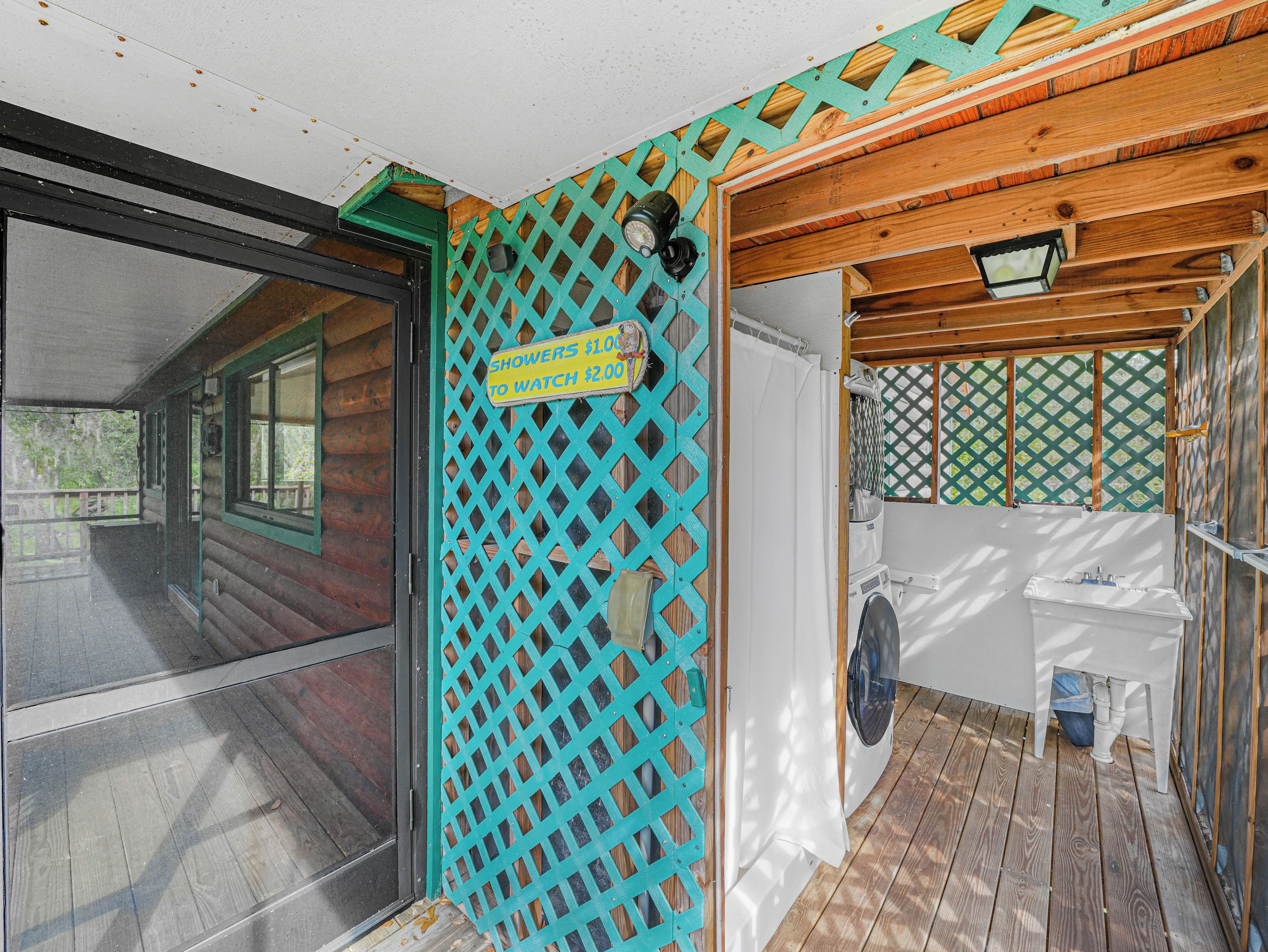 A wooden cabin with a screened porch, a washing machine, and a sign indicating showers and a watch service.