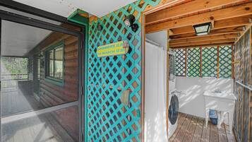 A wooden cabin with a screened porch, a washing machine, and a sign indicating showers and a watch service.