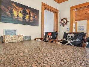 A room with a granite countertop, a welcome sign, a ship wheel, and two chairs with skull-themed pillows. - Enjoyable 1-bedroom cabin with AC in charming Arcadia on Peace River (Arcadia)