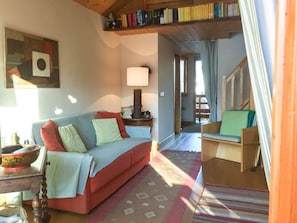 Ein gemütliches Wohnzimmer mit einer Couch, einem Beistelltisch, einer Lampe und einem Bücherregal.
