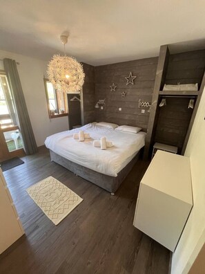 Quarto moderno com uma cama grande, luminária pendente e guarda-roupa.
