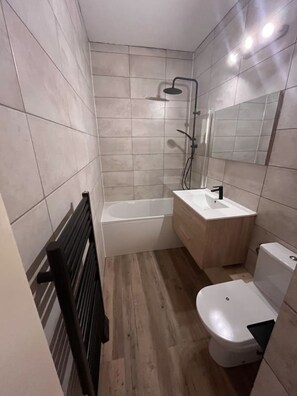 Uma casa de banho moderna com chuveiro, sanita e lavatório.