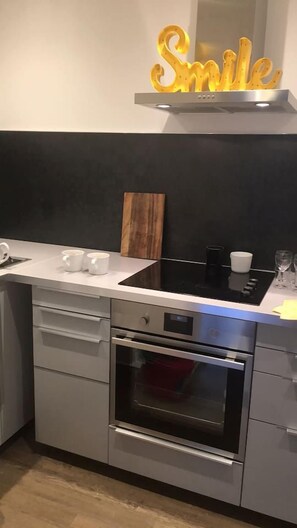 Een keuken met een roestvrijstalen oven, een wit aanrecht en een houten snijplank.