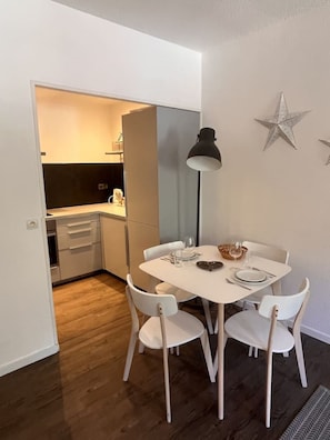 Ein Essbereich mit einem weißen Tisch, gedeckt für vier Personen, einer schwarzen Stehlampe und einer Stern-Dekoration an der Wand.