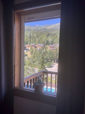 Ein Fenster mit Blick auf eine gebirgige Landschaft und ein Gebäude mit einer Holzterrasse.