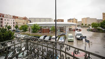 A city street with parked cars, a covered market area, and buildings in the background.