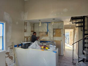 A room under renovation with exposed walls, a staircase, and construction materials. - Nigh Noon - Ocean view, 50 yards to the beach (Surf City)
