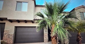 A two-story house with a garage door, a stone pillar, and a palm tree in the foreground. - TRAILHEAD HIDEAWAY ... A LOVELY 3-BEDROOM TOWNHOME IN WASHINGTON, UTAH (Washington)