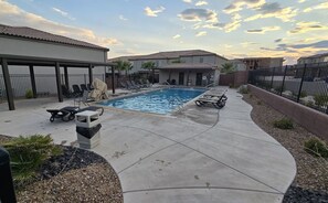 Un espace piscine résidentiel avec des chaises longues et un patio couvert.