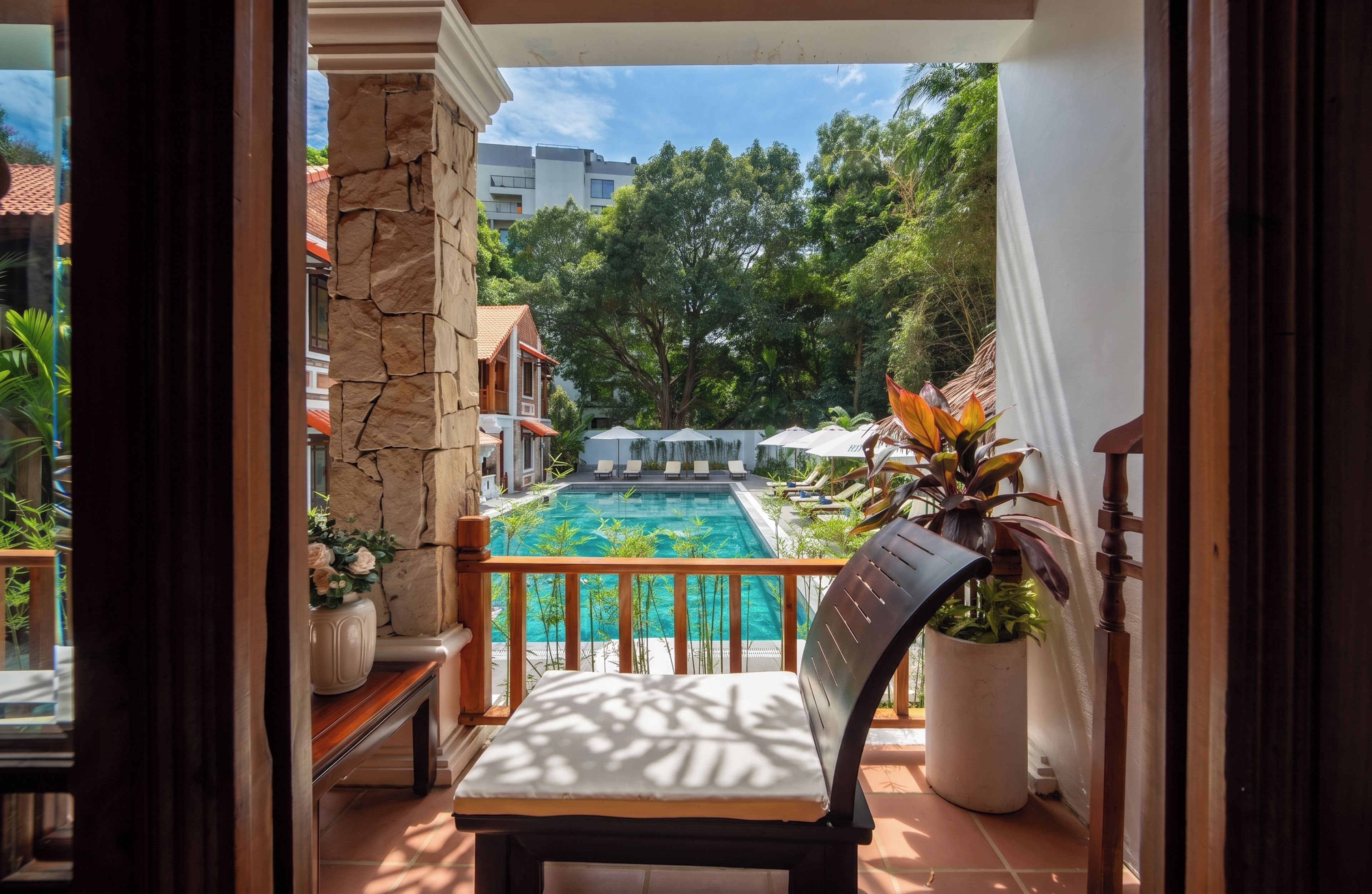A balcony with a view of a swimming pool, a stone wall, and a chair.
