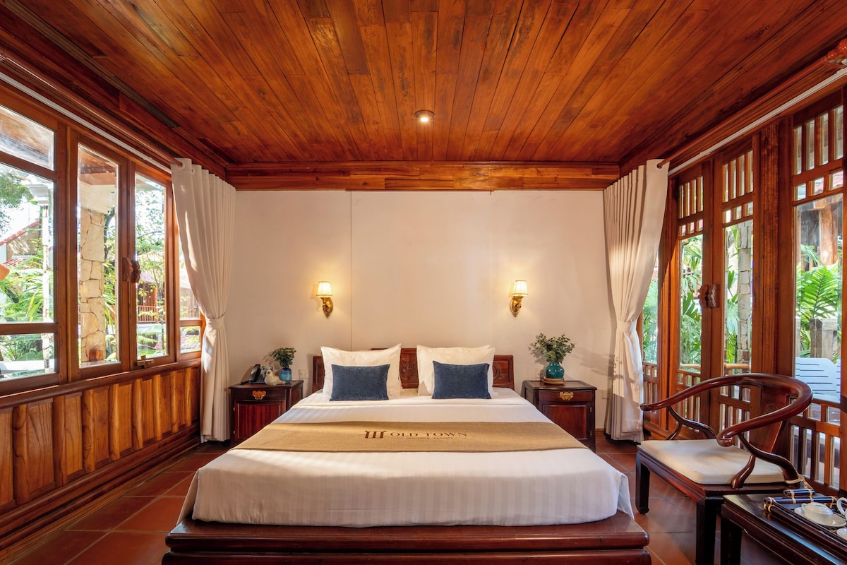 A large bed with a wooden headboard, two bedside tables, and a chair.