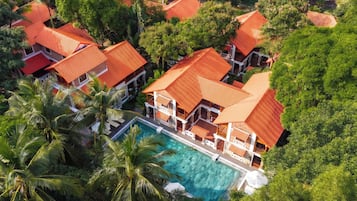 A resort with multiple buildings, a swimming pool, and lush greenery.