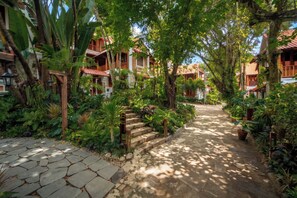 A pathway leading to traditional-style buildings surrounded by lush greenery and stone steps. - Old Town Boutique Resort (Phu Quoc)