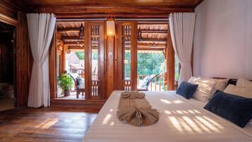 Habitación de hotel con techo de madera, cama con toalla y vista al exterior.