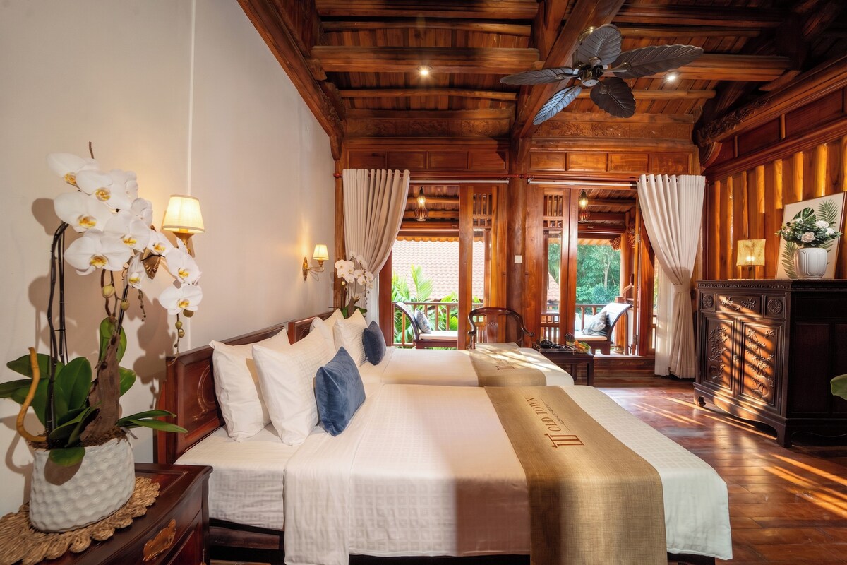 A hotel room with two beds, wooden ceiling, and a view of the outdoors.