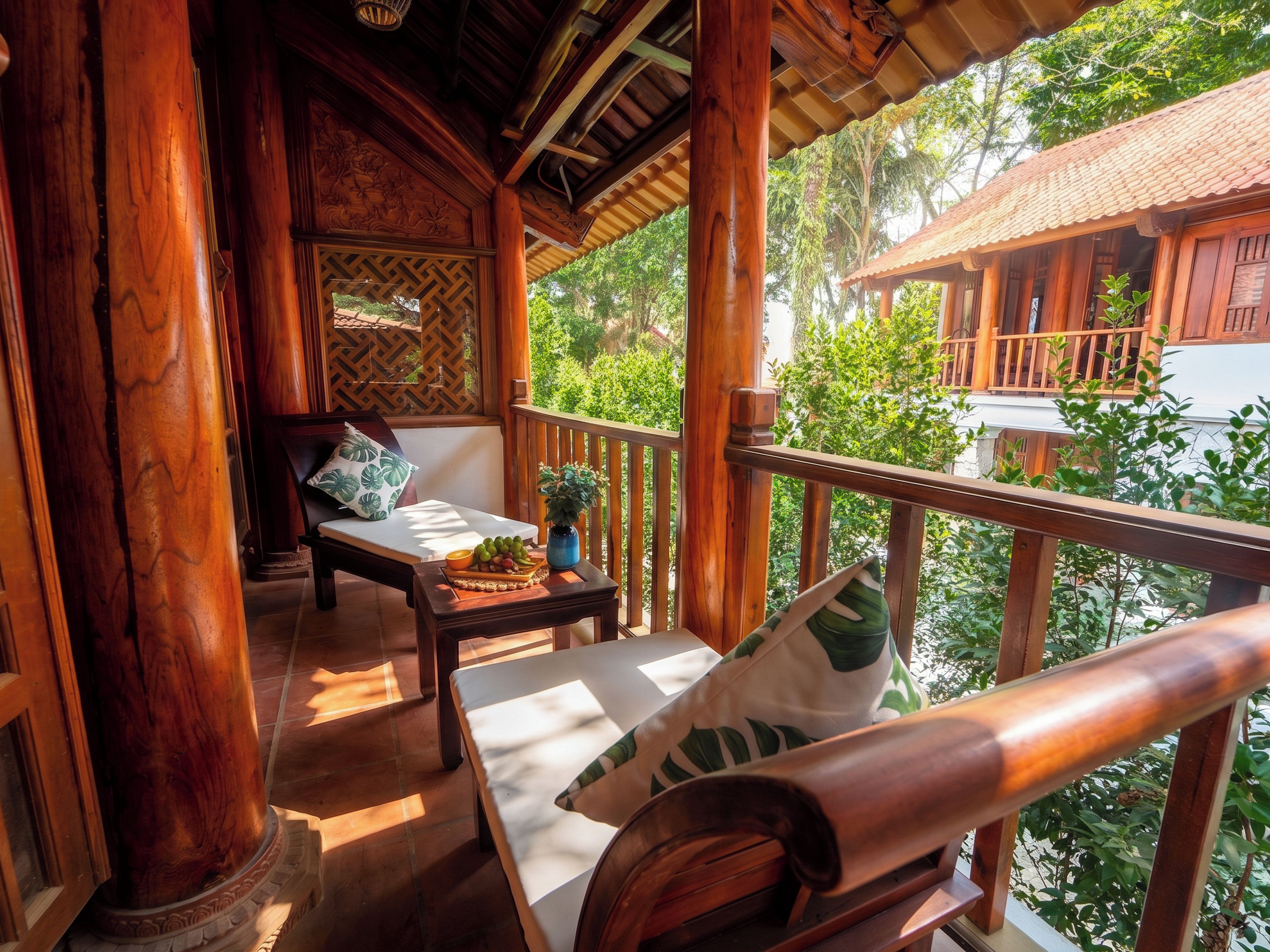 A wooden balcony with a cushioned seating area, a small table with a fruit bowl, and a potted plant.