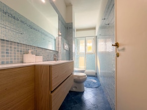 A bathroom with a wooden vanity, a toilet, and a shower area. - Versilia Escape Seaside Retreat (Camaiore)