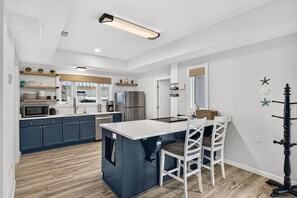 Une cuisine moderne avec un îlot central, des tabourets de bar et un réfrigérateur.