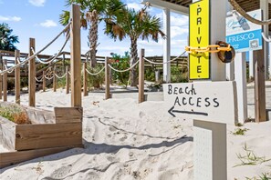 Un panneau indiquant l’accès à la plage, portant une marque privée, une clôture en bois et un panneau indiquant le nom de l’établissement : « Notre hébergement pour les clients ».