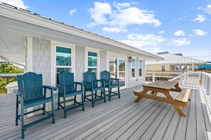 A covered outdoor deck with wooden furniture and a view of the ocean. - Steps to the Beach | Sleeps 13 | 2 Living Spaces (Port St Joe)