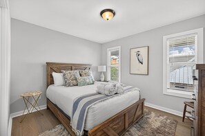 A bedroom with a bed, bedside table, lamp, and artwork on the wall. - Steps to the Beach | Sleeps 13 | 2 Living Spaces (Port St Joe)