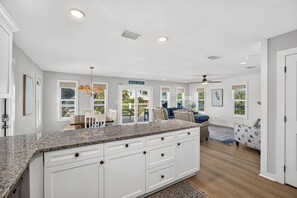A spacious kitchen with white cabinetry, granite countertops, and a dining area with a table and chairs. - Steps to the Beach | Sleeps 13 | 2 Living Spaces (Port St Joe)