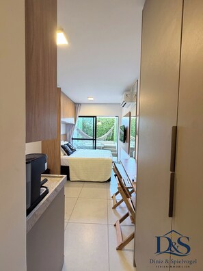 A narrow hallway leading to a bedroom with a bed, a small kitchen area, and a dining table. - MARÉ Prime Studio – Private Jacuzzi · Infinity Pool · Ocean & Sunset Views (Tamandaré)