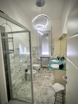 A bathroom with a glass shower enclosure, a white toilet, a glass sink, and a mirror. - SOGNI SUL MARE 5 TERRE-JRE (La Spezia)