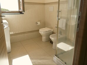 Ein Badezimmer mit Toilette, Bidet und einer Duschkabine aus Glas.