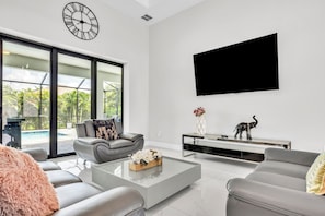 Ein modernes Wohnzimmer mit einem grauen Sofa, einem Couchtisch und einem an der Wand befestigten Flachbildfernseher.