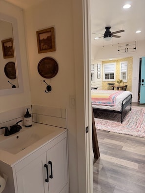 A bedroom with a bed, a bedside table, a dresser, a mirror, and a ceiling fan. - Cozy Cottage on a Working Flower Farm — Private Deck, Fire Pit, Near Sacramento (Loomis)