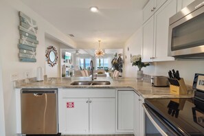 A modern kitchen with a built-in dishwasher, a stainless steel sink, and a microwave. - Largo Mar A165 • Gulf Front Townhome • Outdoor Space + Pool (Panama City Beach)