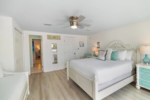A bedroom with a bed, a ceiling fan, a nightstand, and a door leading to another room. - Largo Mar A165 • Gulf Front Townhome • Outdoor Space + Pool (Panama City Beach)