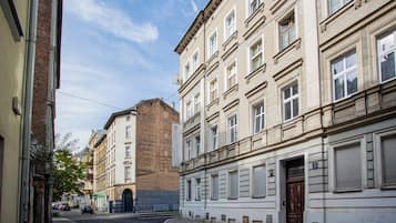 Vista de calle con edificios, incluyendo una construcción de ladrillo y un edificio blanco con un cartel que dice 'Cinema Apartments Hostels'.