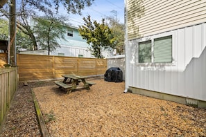 A backyard with a wooden fence, a picnic table, and a covered grill. - A Kure for the Sole 5 bedroom 3 bathroom condo combo. With work from home space (Kure Beach)