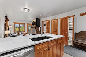 A modern kitchen with a marble countertop, wooden cabinets, and a built-in dishwasher. - Slopeside Luxury at Red Hawk Lodge – Walk to Keystone Gondola (Keystone)